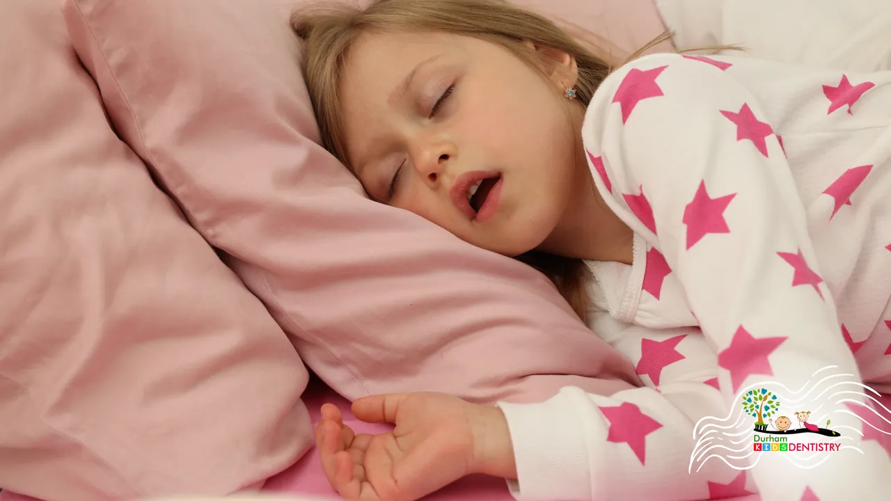 A little girl is sleeping in a bed with a pink pillow.