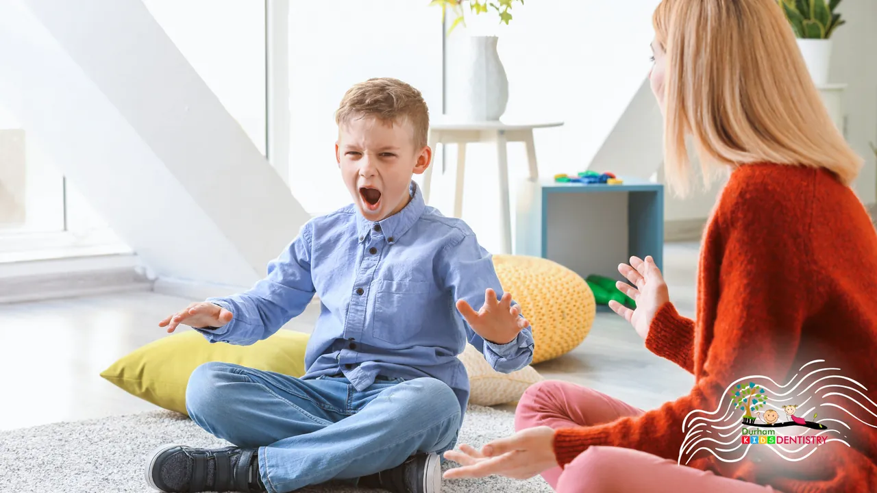 A woman and a boy are sitting on the floor talking to each other.