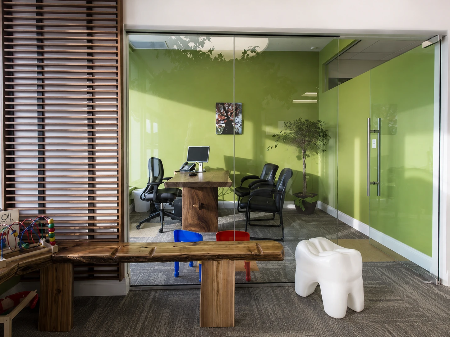 Consultation room with green glass walls and a tooth-shaped stool